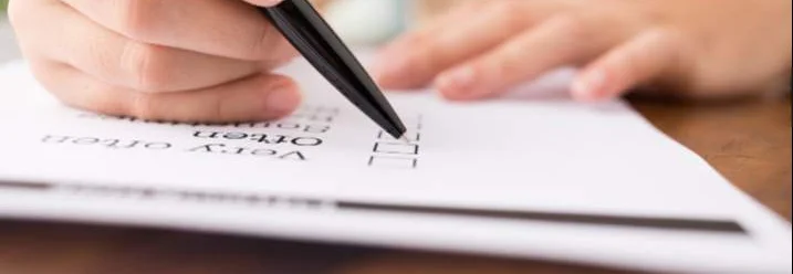 Person hakt etwas mit einem Stift auf einem Blatt Papier ab